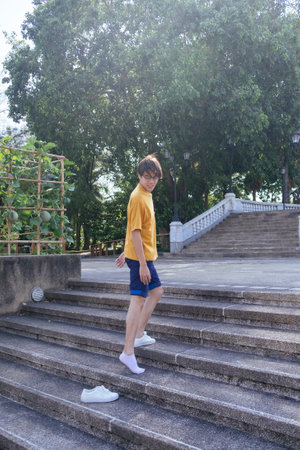 Guy in yellow t-shirt and blue pants walking up the cobblestone stair and leave the shoe behind.の写真素材