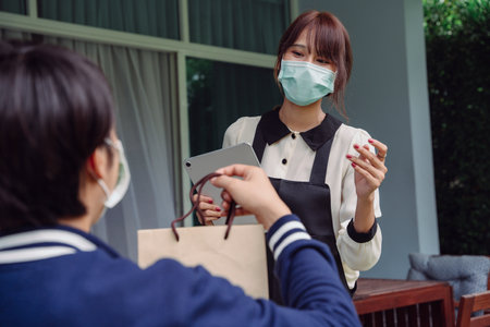 Asian thai woman purchase stuff from online application. Delivery man sent the stuff to her at home.の写真素材