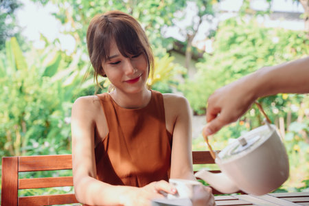 Beautiful asian thai woman taking morning tea at cafe outdoors.の写真素材