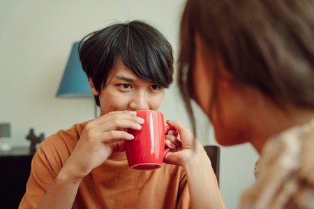 Asian thai couple drinking coffee or water from cup in dinning room. Romantic scene.の写真素材