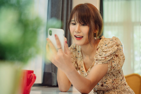 Beautiful asian thai woman using smartphone for online service at home.の写真素材