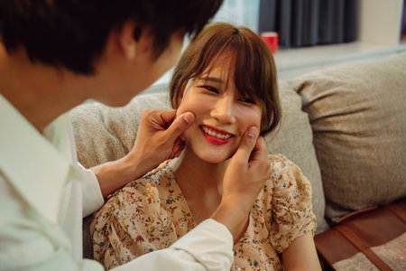 Playful couple. Man playing with woman cheeks by holding with two hands.の写真素材