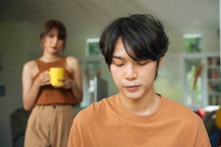 Serious asian man work from home while wife looking at the back. Care and love. New normal.の写真素材