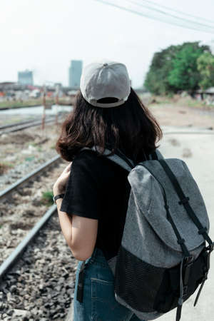 Asian thai backpacker woman traveler waiting for a train on platform.の写真素材