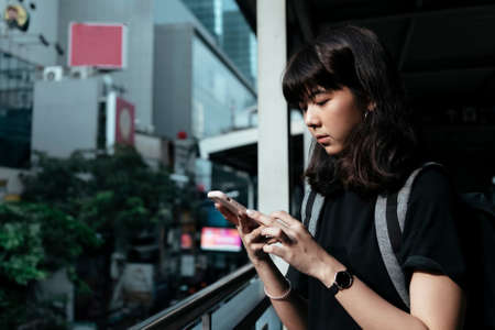 Asian thai backpacker woman using smartphone as a map for travel in the city.の写真素材