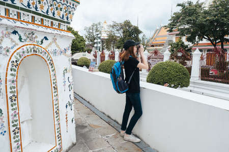 Side view of asian backpacker woman taking picture with camera at wat arun.の写真素材