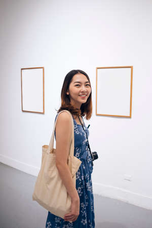 Young asian thai woman in blue dress enjoy sightseeing in artwork gallery.の写真素材