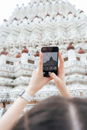 Hand of woman taking picture with smartphone at thai temple wat arun.の写真素材