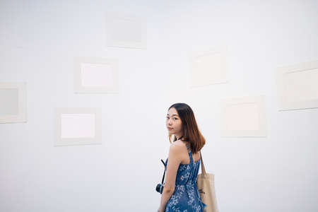 Young asian thai woman in blue dress in white art gallery.の写真素材