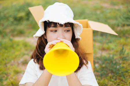 Young asian thai woman hipster curly hairstyle on white dress and hat speaking with yellow toy megaphone.の写真素材