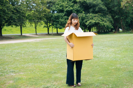 Young asian thai woman hipster curly hairstyle on white shirt carrying cardboard box.の写真素材