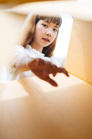 Woman open cardboard box looking inside. Bottom view.の写真素材