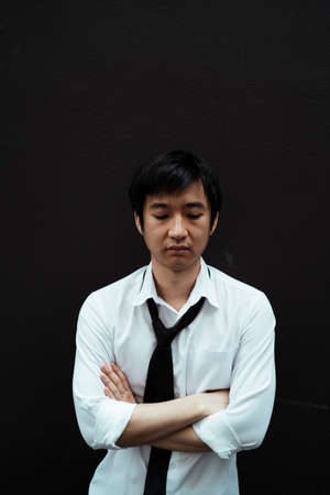 Portrait of stressful asian businessman standing isolated on black background. Bad business day for...