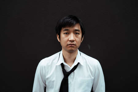 Portrait of stressful asian businessman standing isolated on black background. Bad business day for businessman .の写真素材