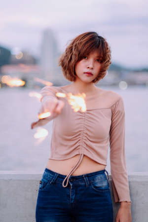 Young sexy asian thai woman short hair in sexy fashion costume and jeans pants playing with firework...