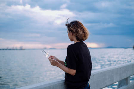 Mystery woman in black shirt holding two sparklers at beach in dusk time.