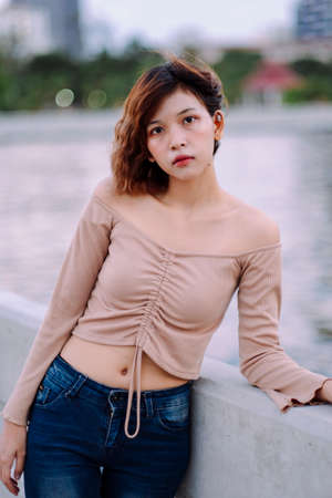 Fashion portrait - Young asian thai woman in sexy shirt and jeans pants on the sea bridge at dusk...