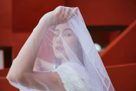 Close up - Portrait of hipster young asian long dark hair woman bride with white veil.