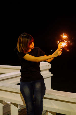 Young asian thai woman playing with sparkler at night.