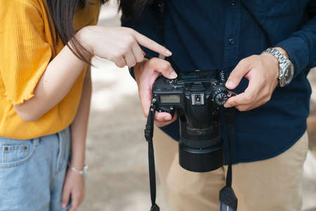 Cropped image of camera while photographer and model look at the photo they take, the model point to the photo.の写真素材