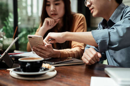 Three young business people looking at the schedule on smartphone. Business people discussing and looking at smartphone.の写真素材