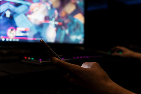 Close hand gamer using mobile phone at internet cafe.の写真素材