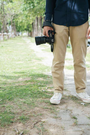 Croped image of digital camera while the male photographer hold it at his lag with copy space.