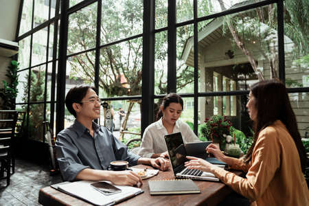 Three young business people looking at the schedule on smartphone. Business people discussing and looking at smartphone.の写真素材