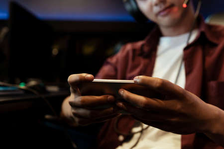 Close up hand of asian gamer playing mobile game with smartphone.の写真素材