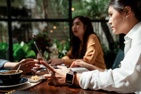 Three young business people looking at the schedule on smartphone. Business people discussing and looking at smartphone.の写真素材