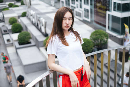 Fashion portrait - Beautiful asian young woman in white shirt and red sport pant posing on over...