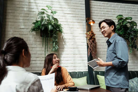 Three young asian business people using tablet in the meeting to explain their business concept and idea.の写真素材