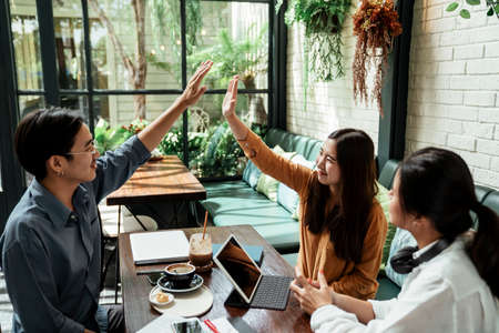 Three young business people looking at the schedule on smartphone. Business people discussing and...
