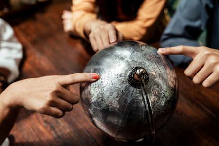 Top view - Three finger pointing at worldglobe. Travel and destination concept.