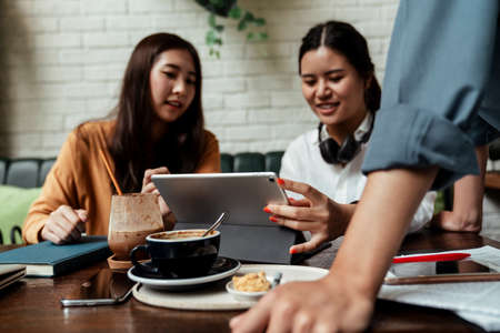 Three young business people looking at the schedule on smartphone. Business people discussing and...