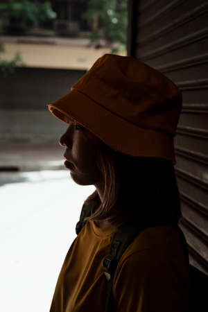 Yellow backpacker woman with green backpack standing in front of the folding door in the shadow avoid the sunlight.の写真素材