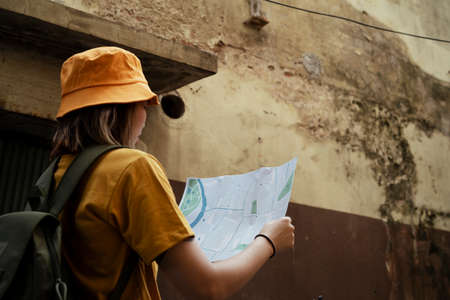 Backpacker girl get lost in the old city, she looking at the map in her hands to locate herself.の写真素材