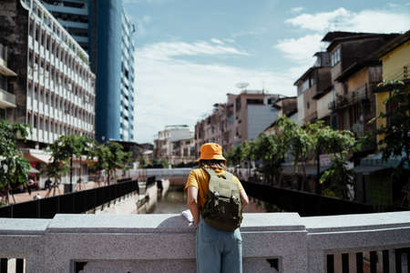 Yellow backpacker woman with green backpack standing at the bridge across the canal in the old town.の写真素材