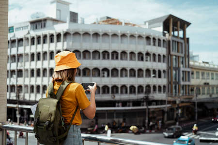 Yellow backpacker woman with green backpack standing on the overpass above the junction in the city.の写真素材