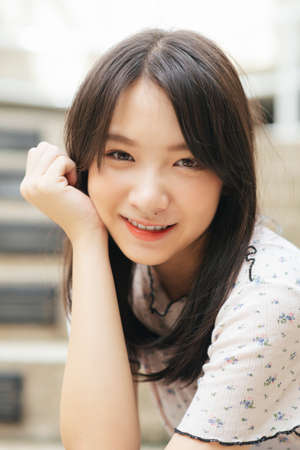 Portrait shot of black long hair girl in white shirt with beautiful smile and charming eyesight.の写真素材
