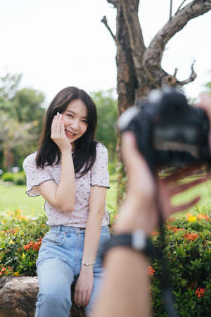 Over shoulder shot of model girl while take a photo at ixora bush.の写真素材