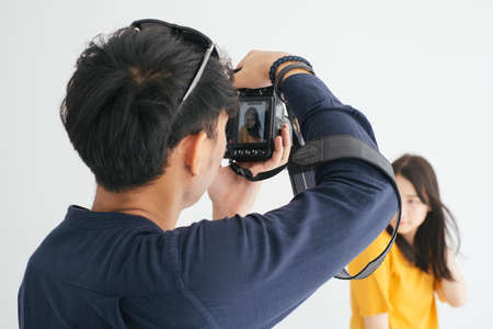 Male photographer take a photo of teenage model girl in the studio with white background.の写真素材