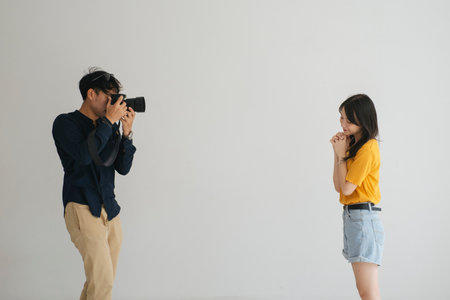 Male photographer take a photo of teenage model girl in the studio with white background.の写真素材