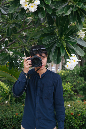 Male camera shooting under the plumeria tree.