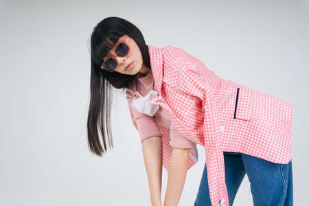 Fashion portrait - Beautiful asian thai long dark hair woman in pink jacket wearing sunglasses over white background.の写真素材