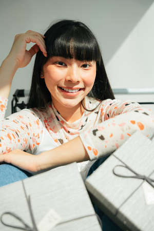 Beautiful asian thai long dark hair woman sit in shopping cart with gift box. Bang hairstyle.