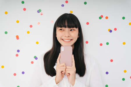 Cheerful beautiful asian thai long dark hair woman with smartphone isolate over white background. Young female with phone.の写真素材