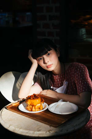 Beautiful asian thai long dark hair woman with bread cake at bakery shop in the morning.