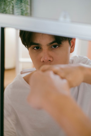 Black hair guy punch his reflection in the mirror with right fist.の写真素材