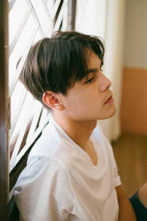 Cool guy with short hair sit and lean at the window, let his mind fly away.